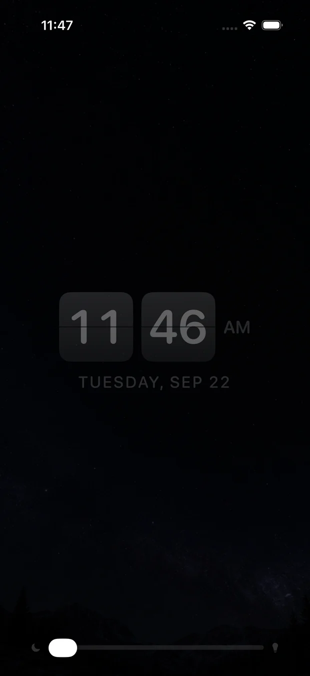 Nightstand mode: a dim split-flap clock over a starfield, with the
                nightlight slider at the bottom.